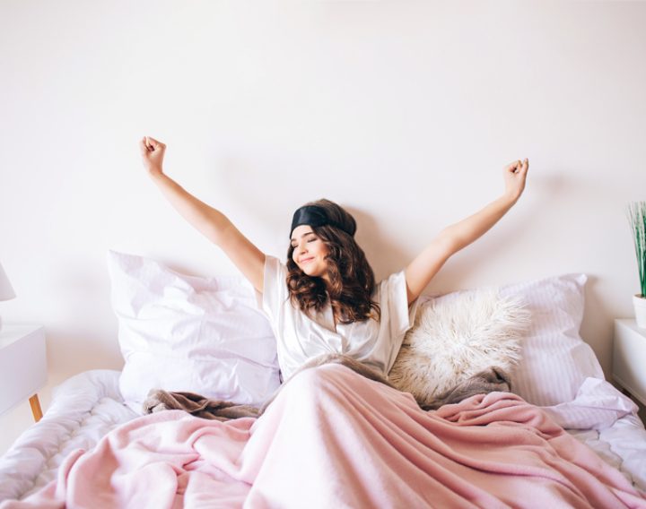 Woman in bed waking up feeling refreshed and energised.